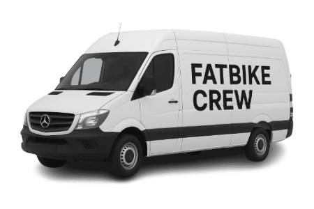 Wit bedrijfsbus met "Fatbike Crew" logo voor fatbike verhuur en evenementen.